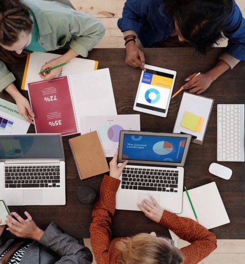 A diverse team collaborating on digital marketing strategies at a desk, using laptops and tablets.