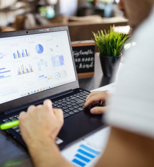 Focused business analysis with charts and graphs on a laptop in a modern office setting.